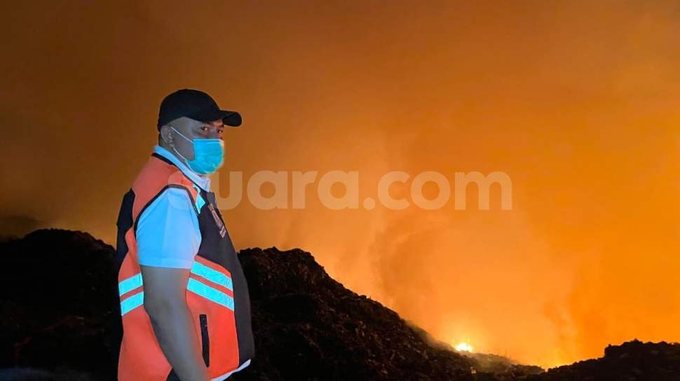 Petugas menggunakan alat berat mengurai tumpukan sampah dan asap di TPA Galuga Bogor